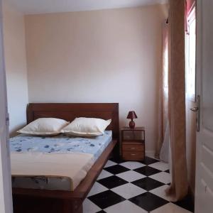 a bedroom with a bed and a black and white checkered floor at VIllAPPART ( appartement au rc) in Antananarivo