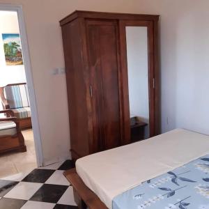 a bedroom with a bed and a wooden cabinet at VIllAPPART ( appartement au rc) in Antananarivo