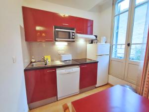 una pequeña cocina con armarios rojos y nevera blanca. en Val de Jade, Le Marmotton, T2, centre Luchon, wifi, casier à skis, 5 personnes en Luchon