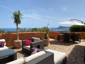 eine Terrasse mit Sofas, einem Tisch und einem Sonnenschirm in der Unterkunft La Morada in Altea
