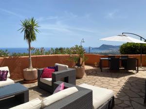 un patio con sofás, una mesa y una sombrilla en La Morada, en Altea