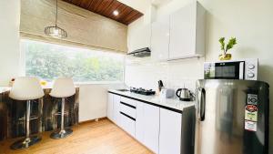 BluO Studio Noida - BathTub, Gym, Balcony, Garden في نويدا: مطبخ مع ثلاجة ستيل ستانلس ودواليب بيضاء