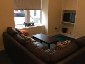 a living room with a leather couch and a table at 103 Nelson Street Ground Right Largs in Largs
