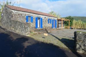 a stone house with blue windows and a stone wall at Casa Vista Fantástica in Pedro Miguel