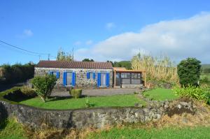 a house with blue doors and a stone wall at Casa Vista Fantástica in Pedro Miguel