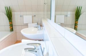 een witte badkamer met een wastafel en een spiegel bij Ferienhaus Kleine Gartenvilla in Pörtschach am Wörthersee