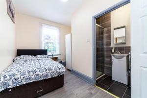 a bedroom with a bed and a shower and a sink at Highlands Gardens Suites in Ilford