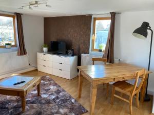 ein Wohnzimmer mit einem Holztisch und einem Schreibtisch in der Unterkunft Ferienwohnung sentio-comfortable Saalfeld in Saalfeld