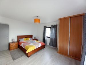 ein Schlafzimmer mit einem Bett und einem Holzschrank in der Unterkunft Casa dos Avós Domingos & Matilde in Estreito da Calheta