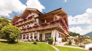 een huis in de bergen met bloemen op de balkons bij Residence Garni Melcherhof in Racines