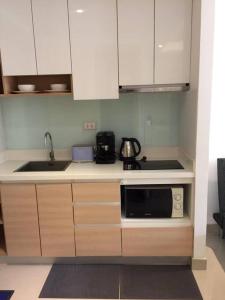 a kitchen with white cabinets and a black microwave at Chaweng Beach Apartment 1 Schlafzi-1Wohnzi-Pool-Fitnes in Ban Ko Khwan