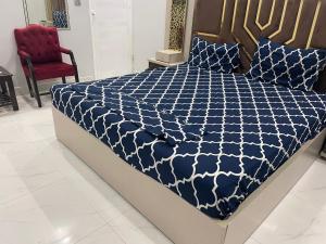- un lit avec une couette bleue et blanche et une chaise rouge dans l'établissement Gulshan Guest House Karachi, à Karachi
