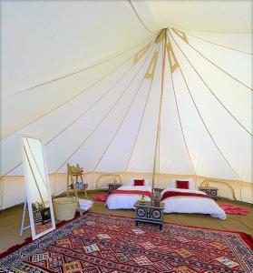 a bedroom with two beds in a large tent at Desert Moments Glamping - full privacy in Muntarib