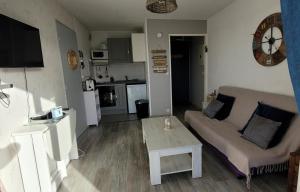 a living room with a couch and a table and a clock at Villers Plage 1 in Villers-sur-Mer