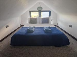 1 dormitorio con 1 cama azul grande y 2 toallas en Bonneys Barn Retreat - Luxury homely getaway, en Burgh Saint Peter