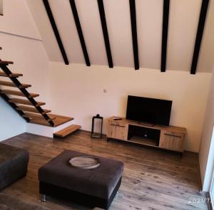 a living room with a flat screen tv and stairs at Kucica na brdu in Zaječar