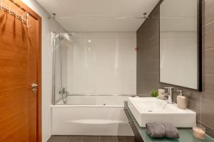 La salle de bains est pourvue d'un lavabo blanc et d'une baignoire. dans l'établissement Modern 2 bedroom apt 20 min from city center, à Amadora