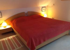 a bedroom with a large red bed with two lights at Ferienwohnung Boddenblick in Zudar