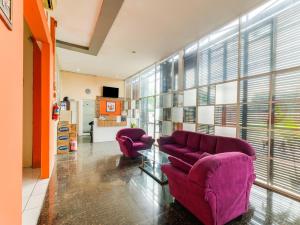 uma sala de estar com duas cadeiras roxas e janelas em SPOT ON 2451 Camel Residence em Semarang