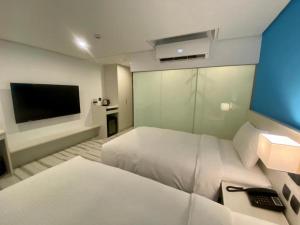 Habitación de hotel con 2 camas y TV de pantalla plana. en JIASHITE HOTEL en Taoyuan
