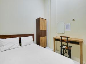 a bedroom with a bed and a wooden desk at SPOT ON 2451 Camel Residence in Semarang