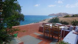 een patio met een tafel en stoelen en uitzicht op de oceaan bij Villa Rodialos in Panormos Rethymno