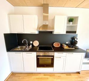 a kitchen with white cabinets and a sink at Bergblick-Apartment in Tirol in Pflach