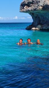 three people swimming in the water in the ocean at El Aplatanao Hotel in Pedernales
