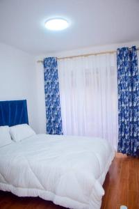 1 dormitorio con 1 cama con cortinas azules y blancas en Complete specious and central apartment in n Nairobi - Kilimani, en Nairobi