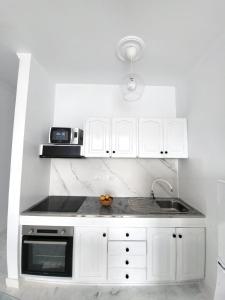 een witte keuken met een wastafel en een magnetron bij Mar Bonanza in Orzola