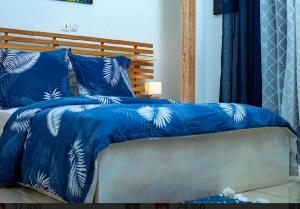 a blue bed with blue and white sheets and pillows at Appartement cosy Green bonapriso in Douala