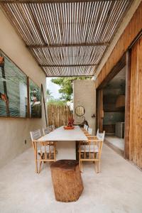 una mesa y sillas en un patio con techo de madera en Pousada Zinga Caraíva, en Caraíva