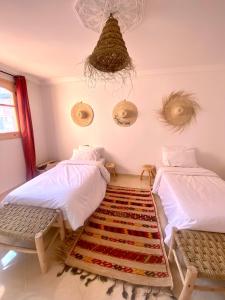 um quarto com duas camas e um tapete no chão em Moana Surf Maroc em Tamraght Ouzdar