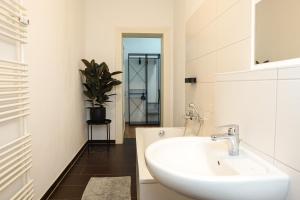een witte badkamer met een wastafel en een potplant bij HOMY I Altbaucharme Netflix und WLAN in Leipzig