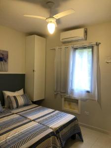 um quarto com uma cama e uma janela em Condominio com muita diversão Toninhas em Ubatuba