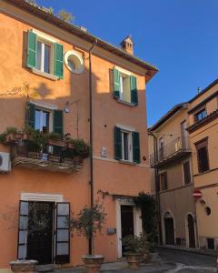 an orange building with green shutters on a street at B & B Beata Colomba in Rieti