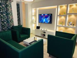 a living room with two green chairs and a tv at Appartement cosy Green bonapriso in Douala