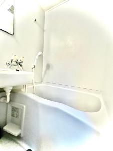 biała łazienka z umywalką i wanną w obiekcie ウィンベル沖縄名護コーラルビュー w mieście Agarii