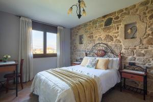 1 dormitorio con 1 cama y pared de piedra en Casas Lar de Arousa I y II, en Catoira