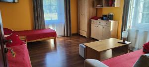 a living room with a red couch and a table at Agroturystyka Przystanek Góry Sowie in Ludwikowice Kłodzkie