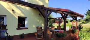 a patio with a wooden pergola and a table and chairs at Agroturystyka Przystanek Góry Sowie in Ludwikowice Kłodzkie