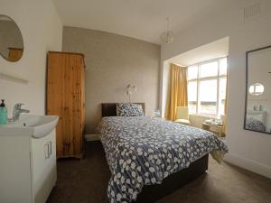 een slaapkamer met een bed, een wastafel en een raam bij Ashdale Guest House in Llandudno