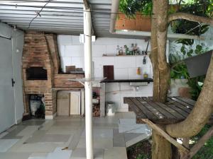 una cocina al aire libre con un banco y un árbol en Casa do Roberto, en Cabo Frío