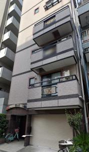 an apartment building with a garage in front of it at honeys guest house in Tokyo