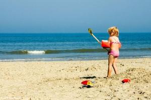 een jong meisje speelt in het zand op het strand bij wadgeluk in Ballum