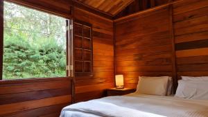 a bedroom with a bed and a large window at Chalé Arado 313 in Monte Verde