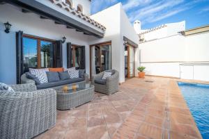 een patio met rieten meubels naast een zwembad bij Stunning detached Villa in El Valle Golf Resort - ZO24EV in Murcia