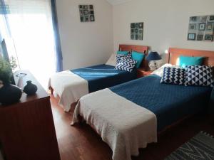 een slaapkamer met 2 bedden met blauwe en witte lakens bij Apartamento Panorâmico das Dunas da Bela Vista in Gafanha da Encarnação
