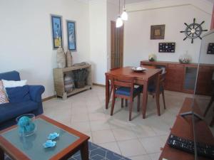 een woonkamer met een blauwe bank en een tafel bij Apartamento Panorâmico das Dunas da Bela Vista in Gafanha da Encarnação