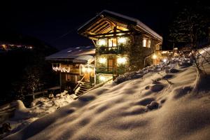 a house with lights in the snow at night at Appartement Gentiane de 85m2 avec sauna à 10 min des pistes in Sainte-Foy-Tarentaise